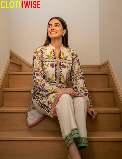 Woman sitting on stairs wearing a patterned kurta with white pants, brand 'CLOTHWISE' visible.