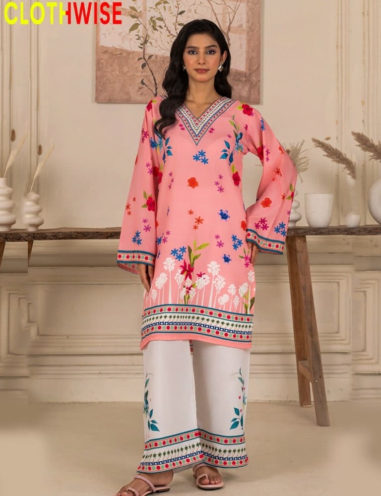 Woman wearing a pink floral outfit with white pants in a decorated room.