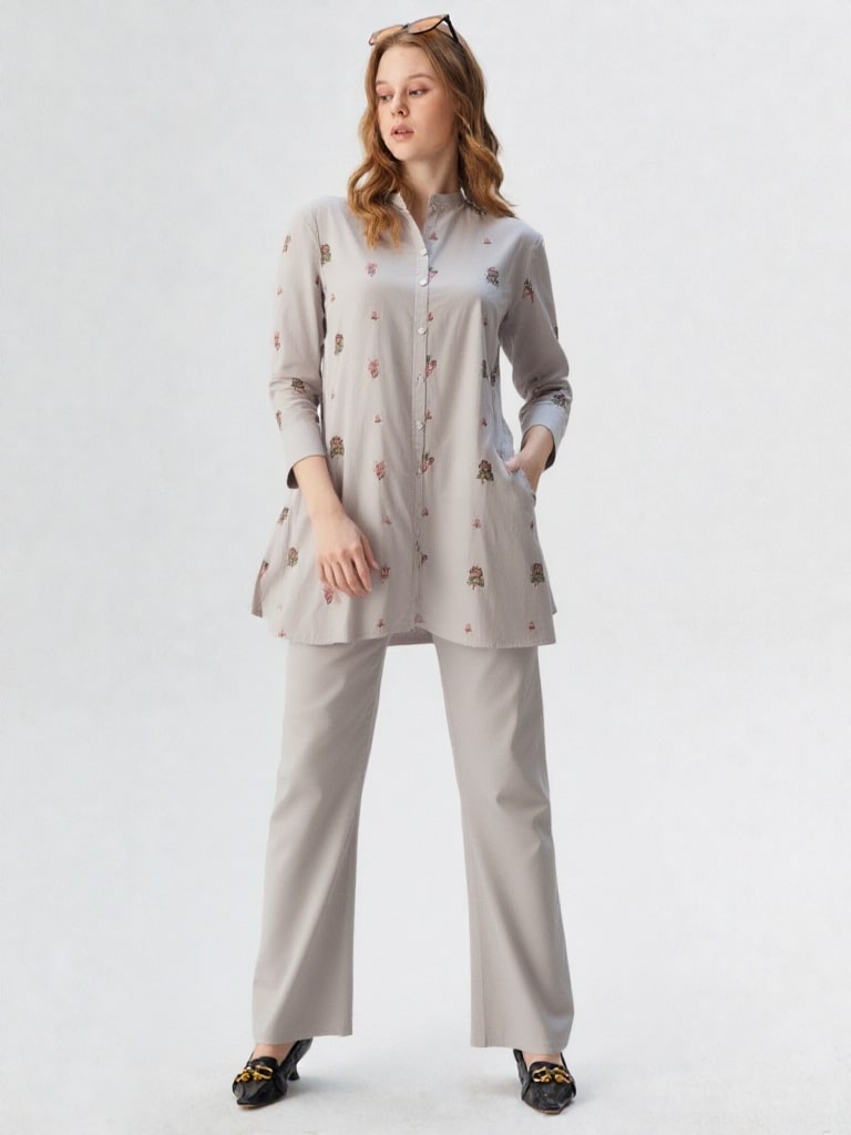 Woman wearing a light gray outfit with a matching top and pants on a white background