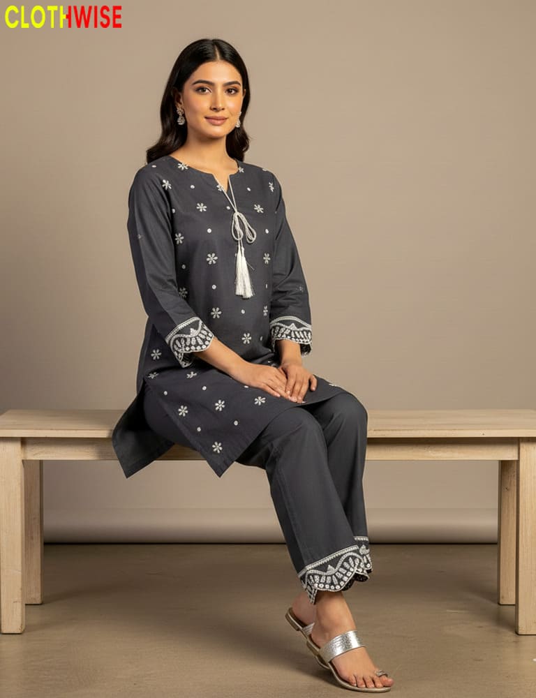 Woman sitting on a bench wearing a dark blue traditional outfit with white patterns, branded 'CLOTHWISE'.