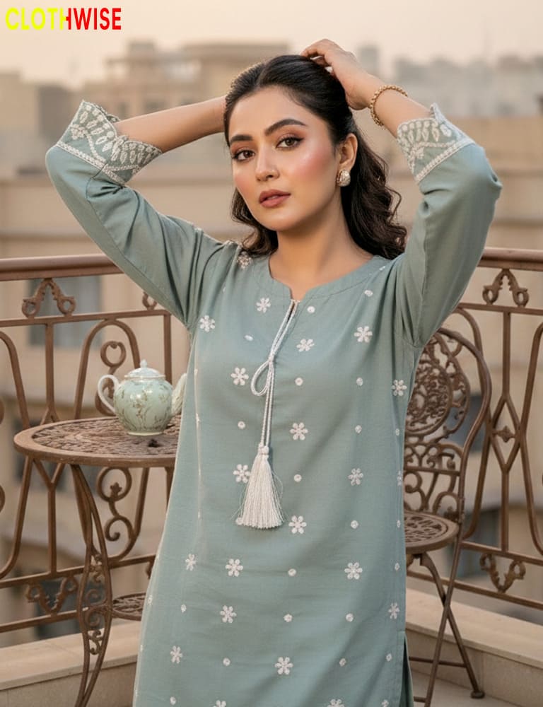 Woman wearing a ice green embroidered kurta on a balcony with 'Clothewise' branding.