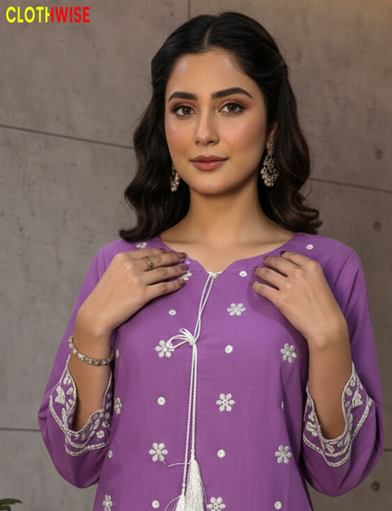 Woman wearing a purple embroidered outfit with a neutral background