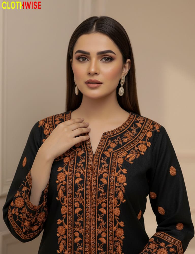 Woman wearing a black outfit with orange embroidery, posing against a neutral background.