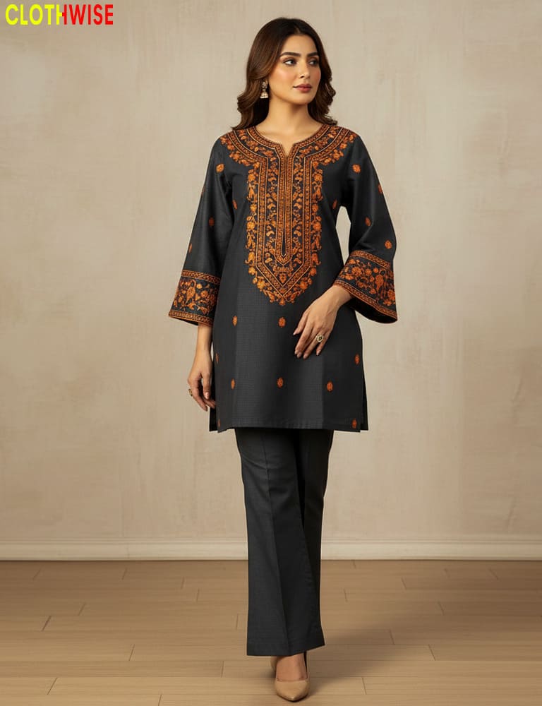 Woman wearing a dark gray traditional outfit with intricate orange embroidery against a plain background.