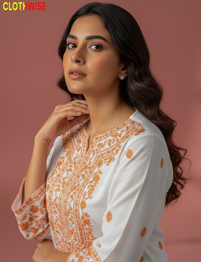 Woman wearing a white and orange embroidered top with a blurred background