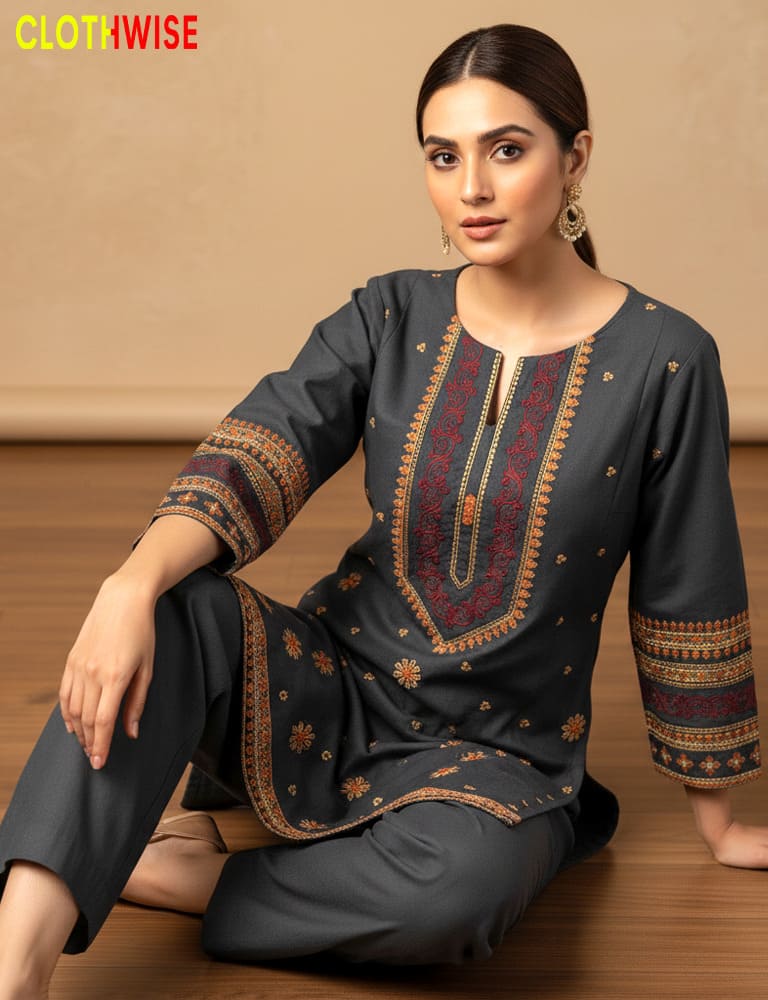 Woman wearing a dark gray traditional outfit with intricate patterns, sitting on a wooden floor.