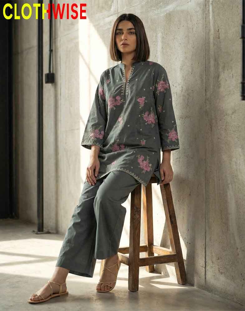 Woman sitting on a wooden stool wearing a gray floral outfit with 'CLOTHWISE' branding.