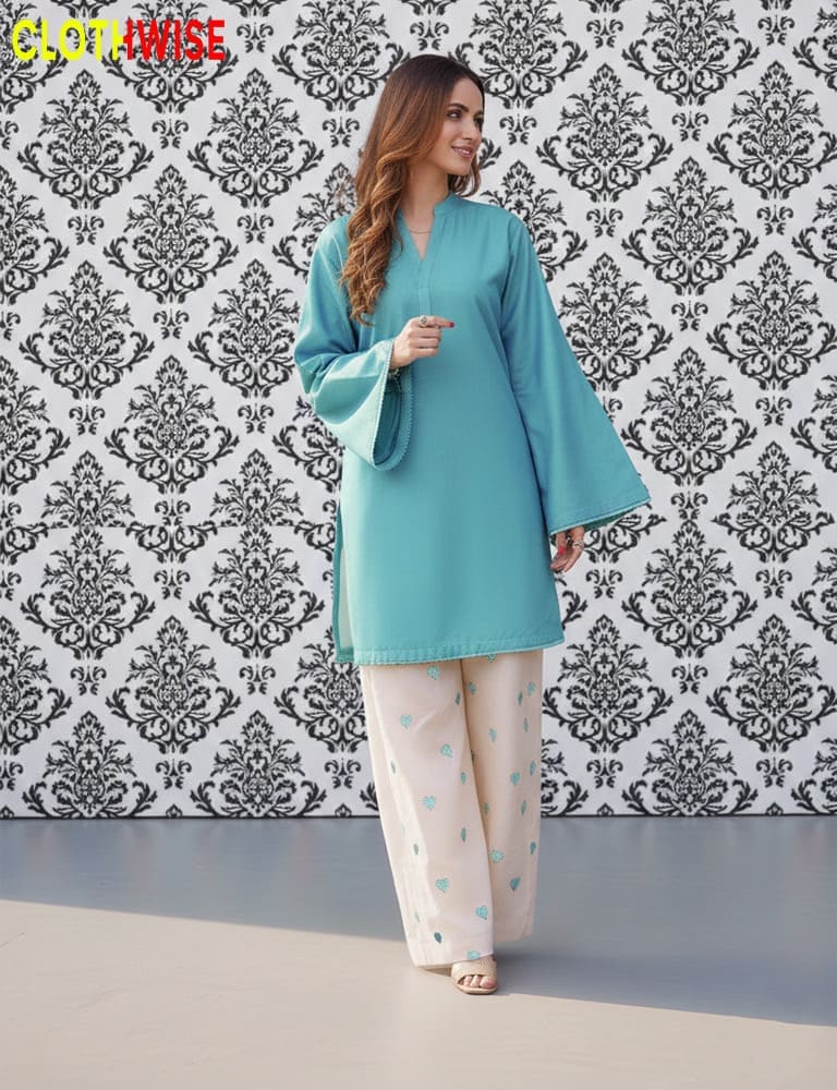 Woman wearing a teal outfit with a patterned wall in the background