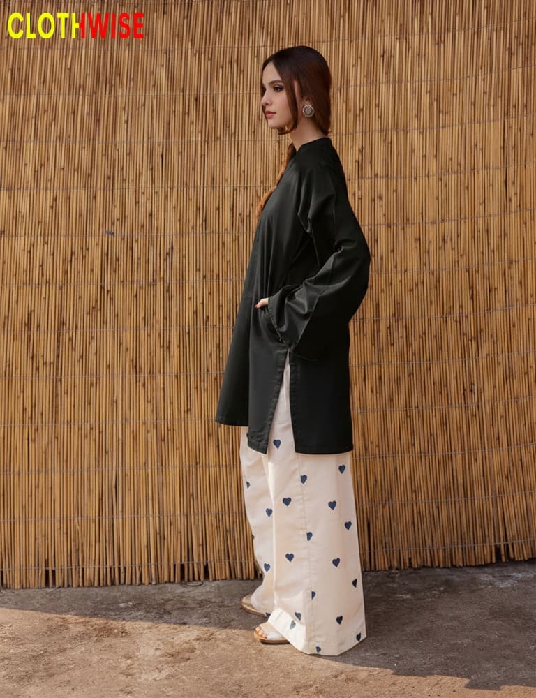 Woman wearing a black top and white pants with heart patterns against a bamboo wall, with 'CLOTHWISE' branding.