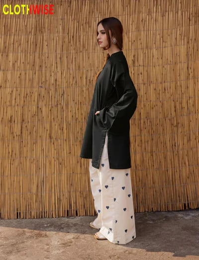 Woman wearing a black top and white pants with heart patterns against a bamboo wall, with 'CLOTHWISE' branding.