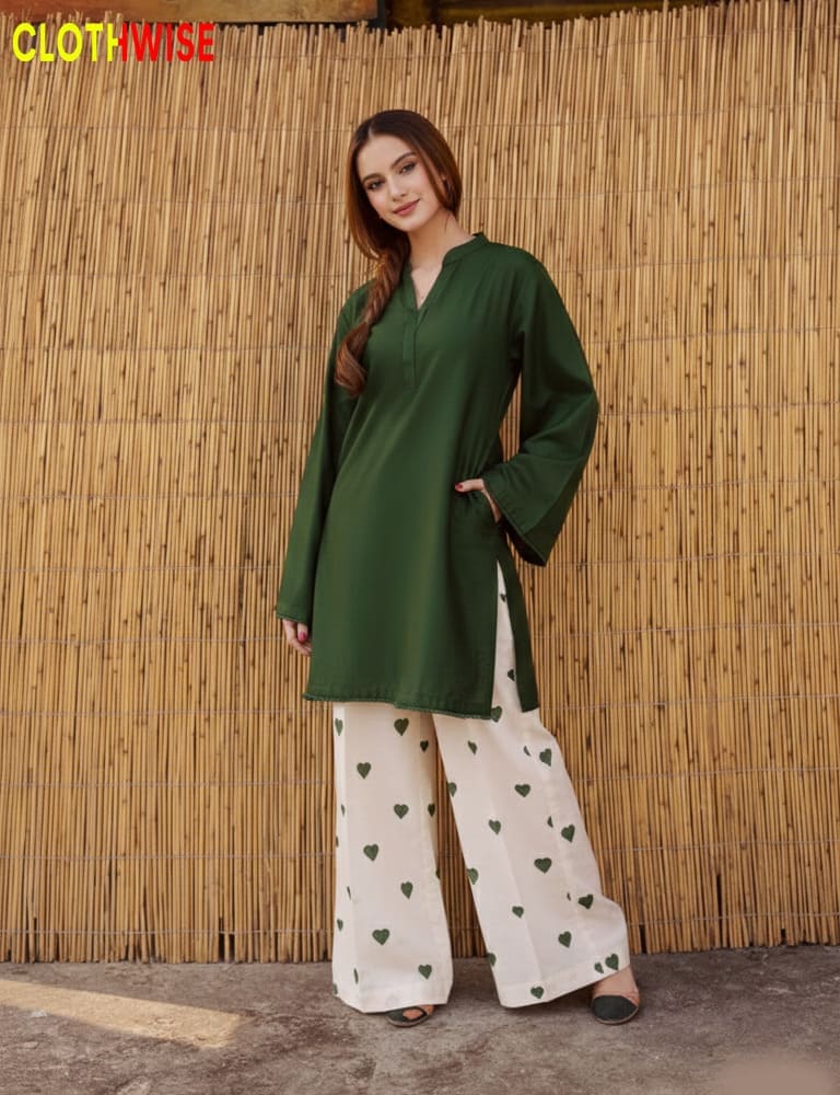 Woman wearing a green top and white pants with heart patterns against a bamboo wall, branded 'Clothwise'.