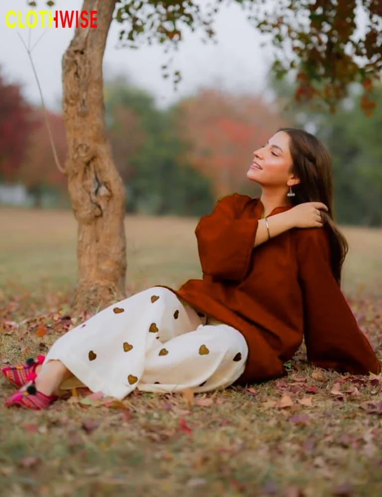 Woman in a brown outfit sitting on the grass with a blurred background