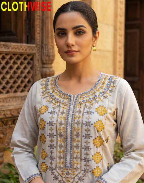 Woman wearing a traditional embroidered kurta with a wooden architectural background