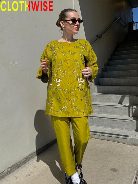 Woman wearing a yellow patterned outfit standing on steps with 'CLOTHWISE' branding.