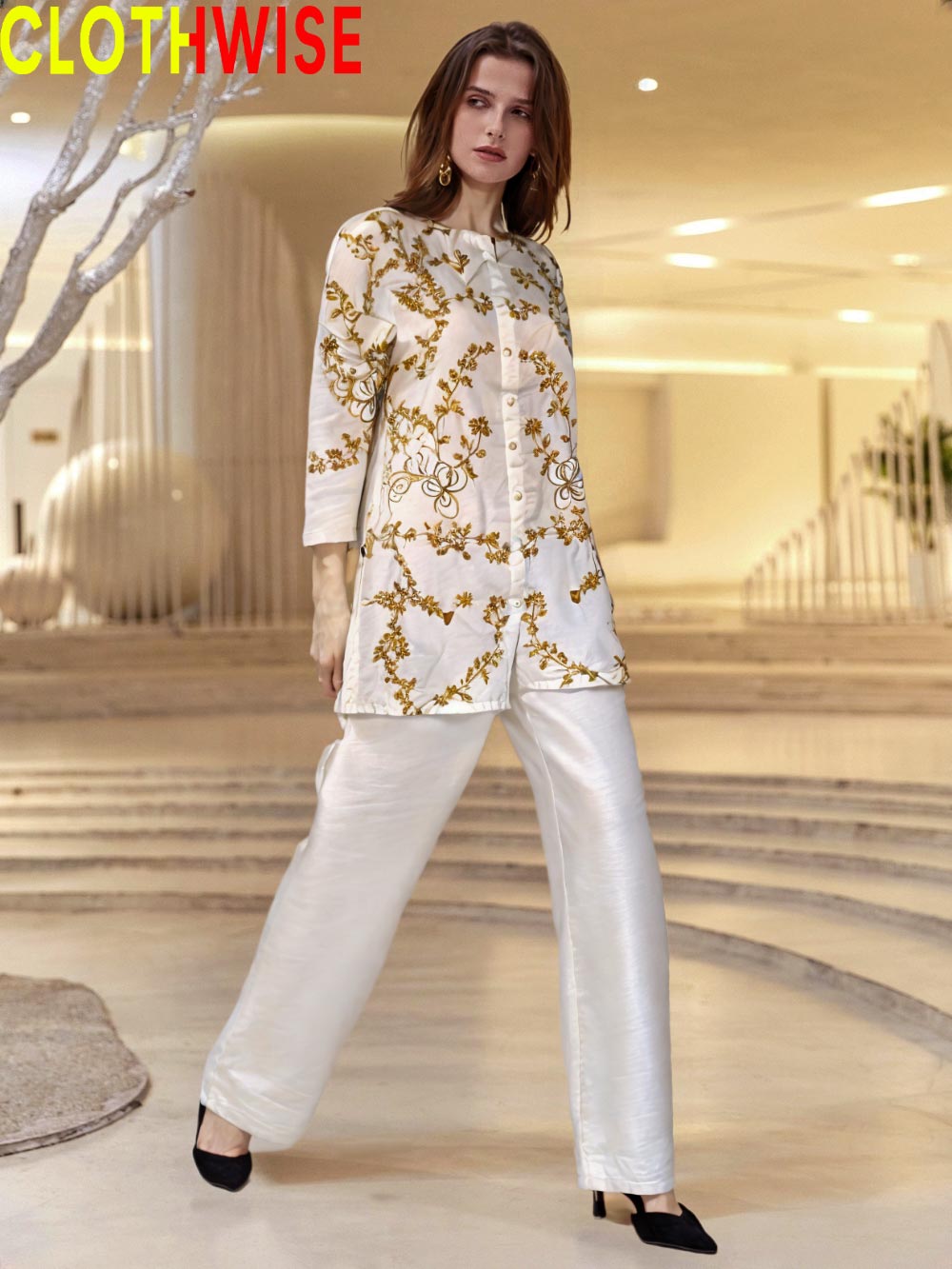 Woman wearing a white outfit with gold embroidery in a modern indoor setting, with 'CLOTHWISE' branding.