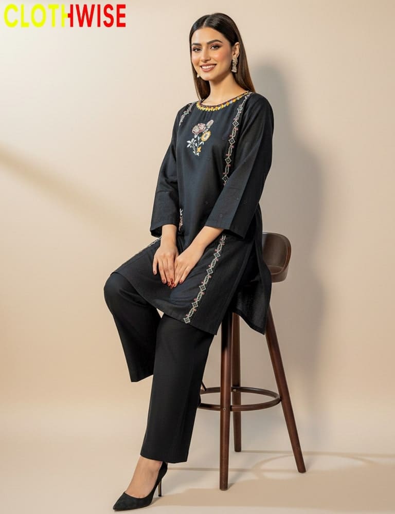 Woman wearing a black outfit with embroidery sitting on a stool against a beige background, with 'CLOTHWISE' branding.