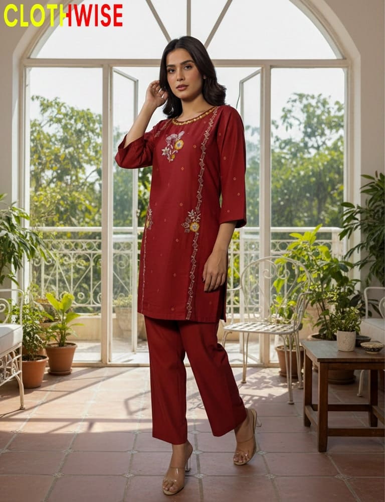 Woman wearing a red outfit with floral patterns in a bright room with large windows and plants.