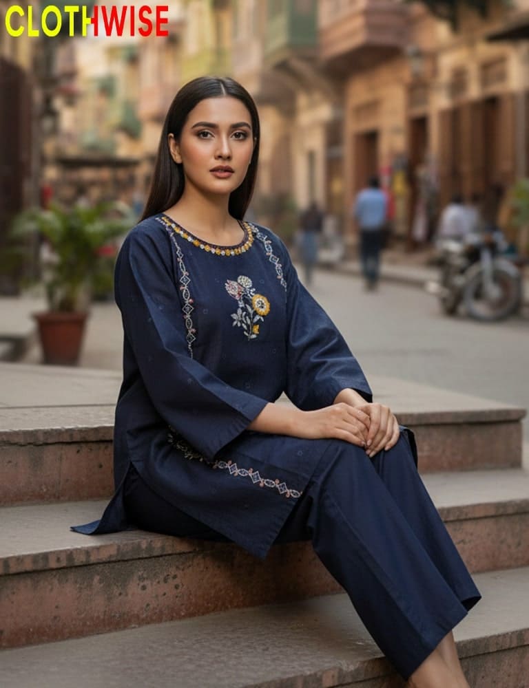 Woman in a blue embroidered outfit sitting on steps with a blurred street scene in the background