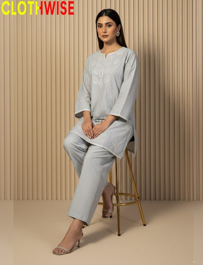 Woman wearing a light gray outfit sitting on a stool against a beige wall with 'CLOTHWISE' branding.