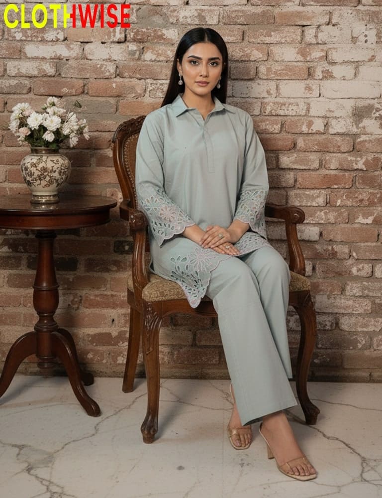 Woman sitting on a wooden chair wearing a light blue outfit with lace details, against a brick wall.