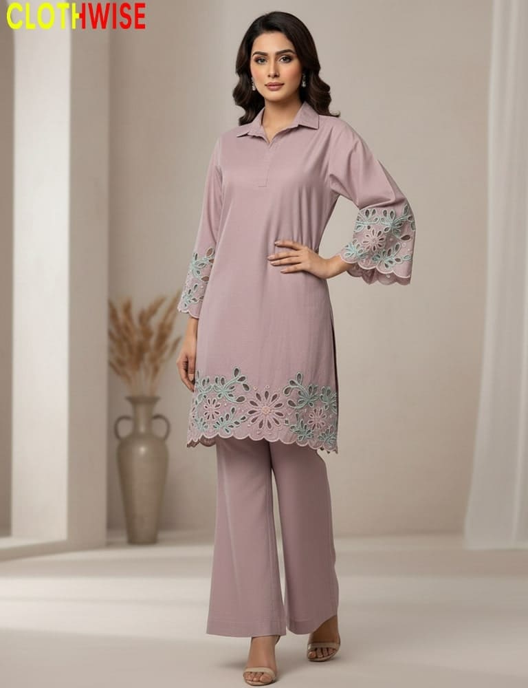 Woman wearing a pink outfit with floral embroidery, standing against a neutral background.