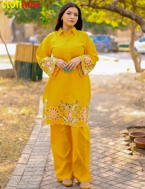 Woman wearing a yellow traditional outfit with floral embroidery outdoors.