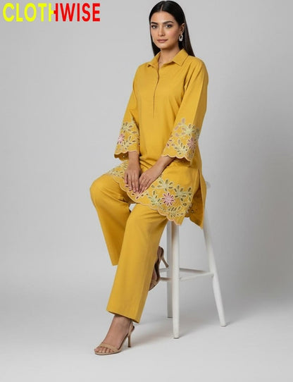 Woman wearing a yellow outfit with floral embroidery sitting on a white stool against a gray background, with 'CLOTHWISE' branding.