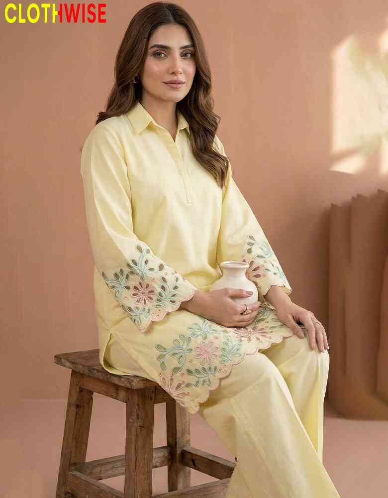 Woman in a light yellow outfit with floral embroidery sitting on a wooden stool, holding a white pot against a beige background.