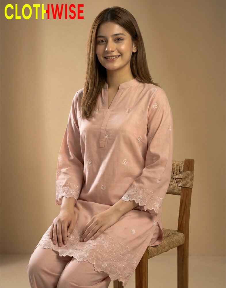 Woman wearing a pink kurta with lace details sitting on a wooden chair against a beige background, with 'CLOTHWISE' branding.