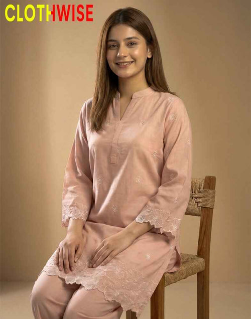 Woman wearing a pink kurta with lace details sitting on a wooden chair against a beige background, with 'CLOTHWISE' branding.