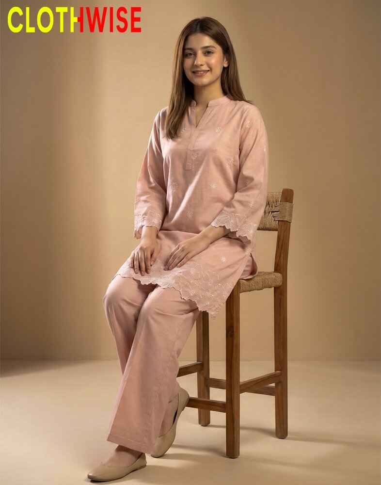 Woman wearing a pink outfit sitting on a wooden chair with 'Clothewise' branding.