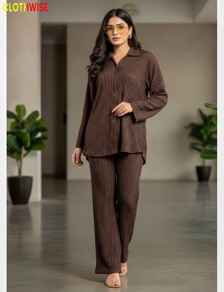 Woman wearing a brown textured outfit in an indoor setting with plants.