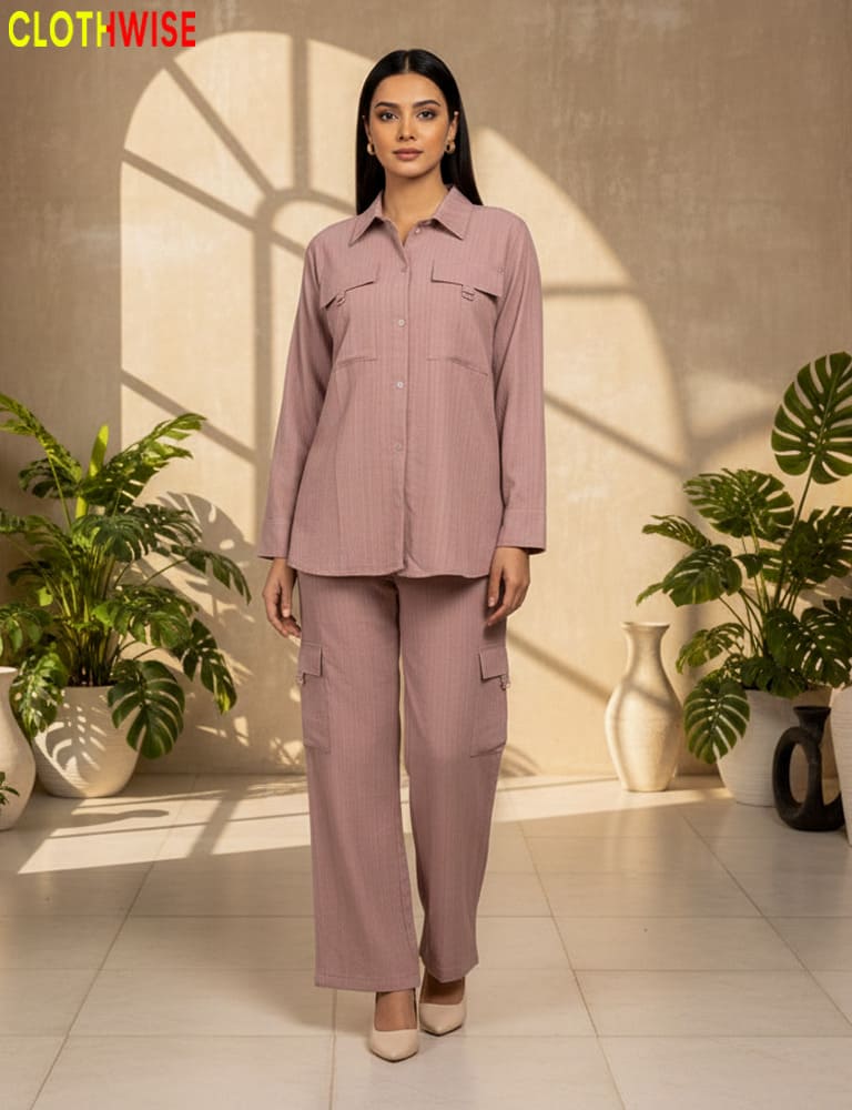 Woman wearing a pink outfit standing in a well-lit room with plants.