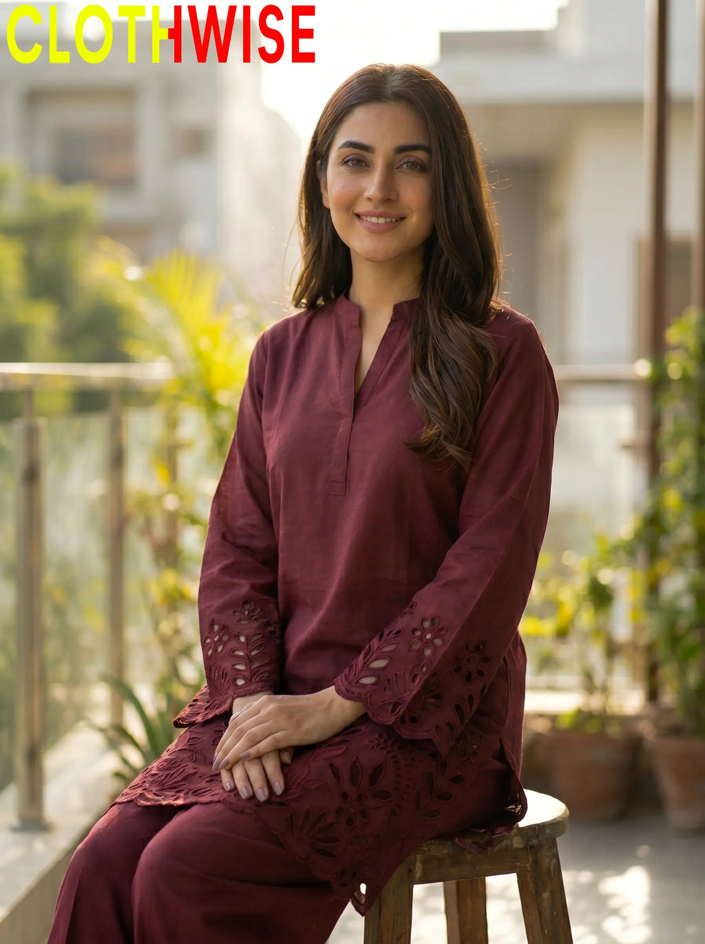 Woman wearing a maroon outfit sitting on a stool with plants and buildings in the background, branded 'CLOTHWISE'.