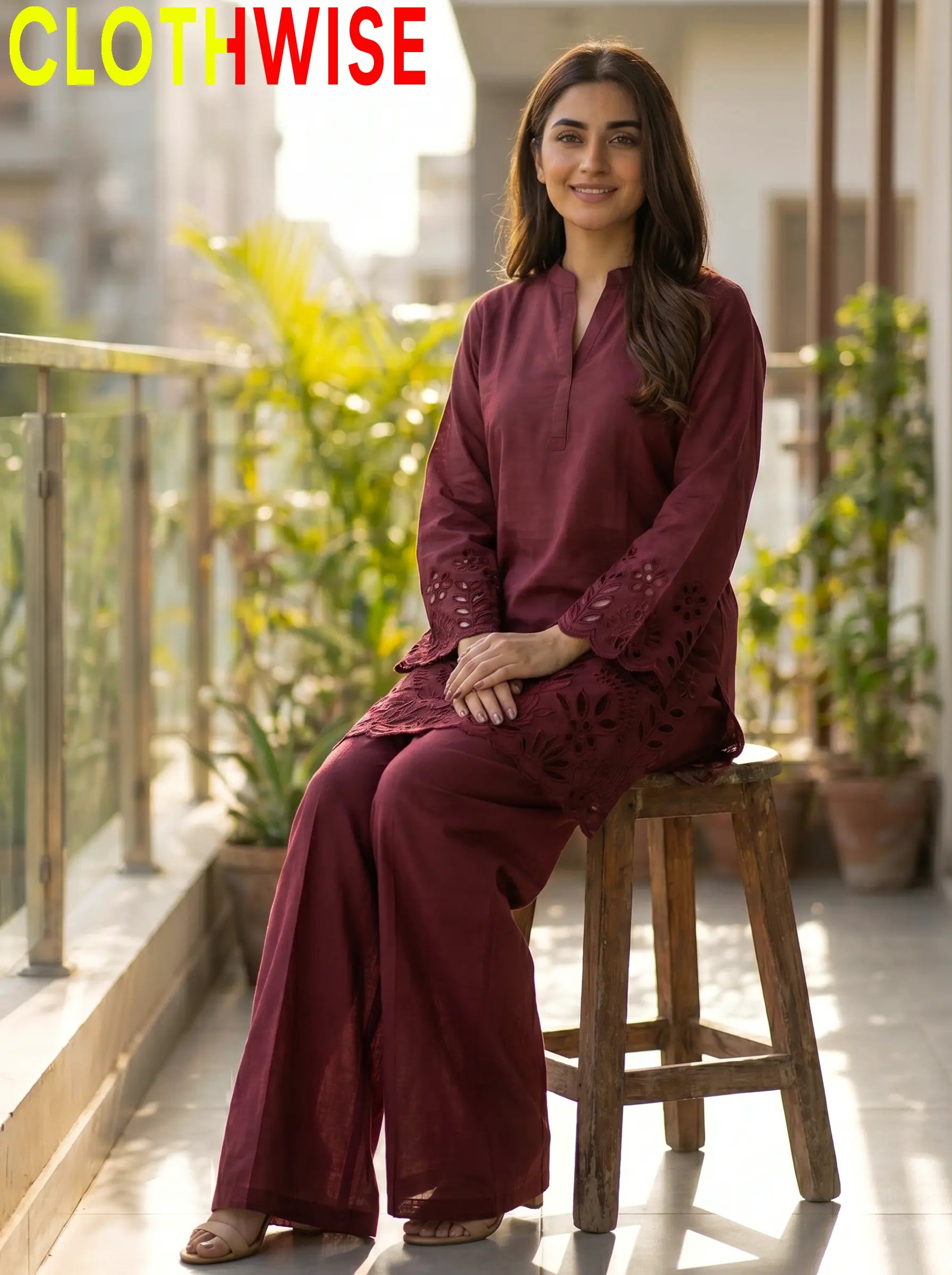 Woman in a maroon outfit sitting on a stool with plants in the background, branded 'CLOTHWISE'.