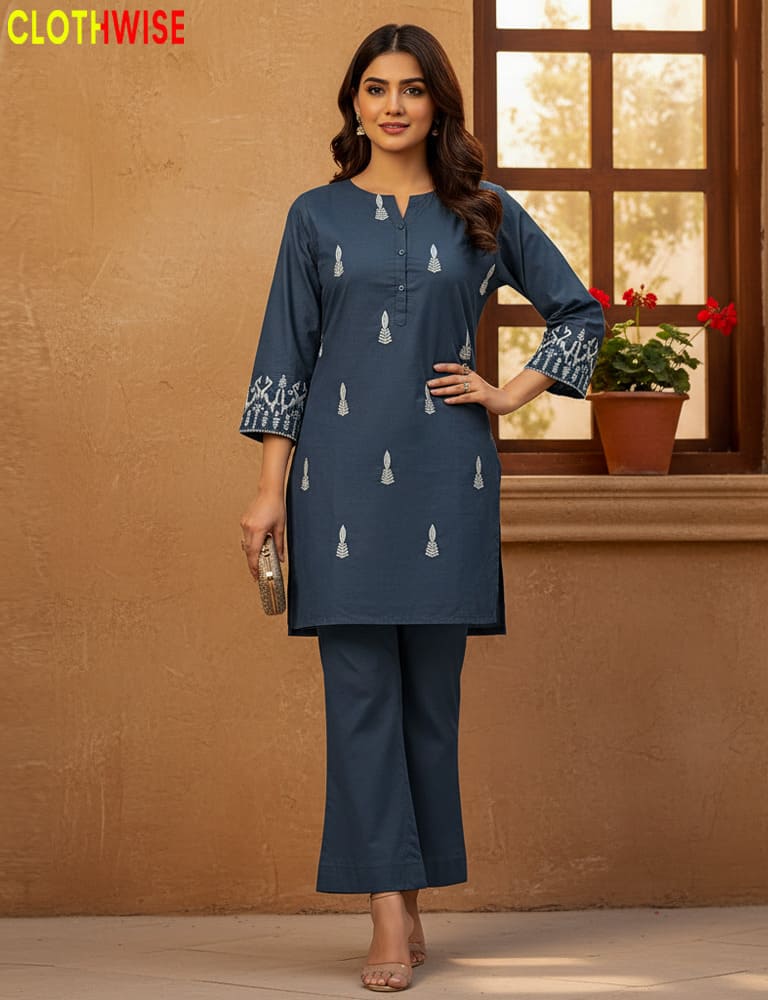 Woman wearing a blue kurta with white patterns against a brown wall.