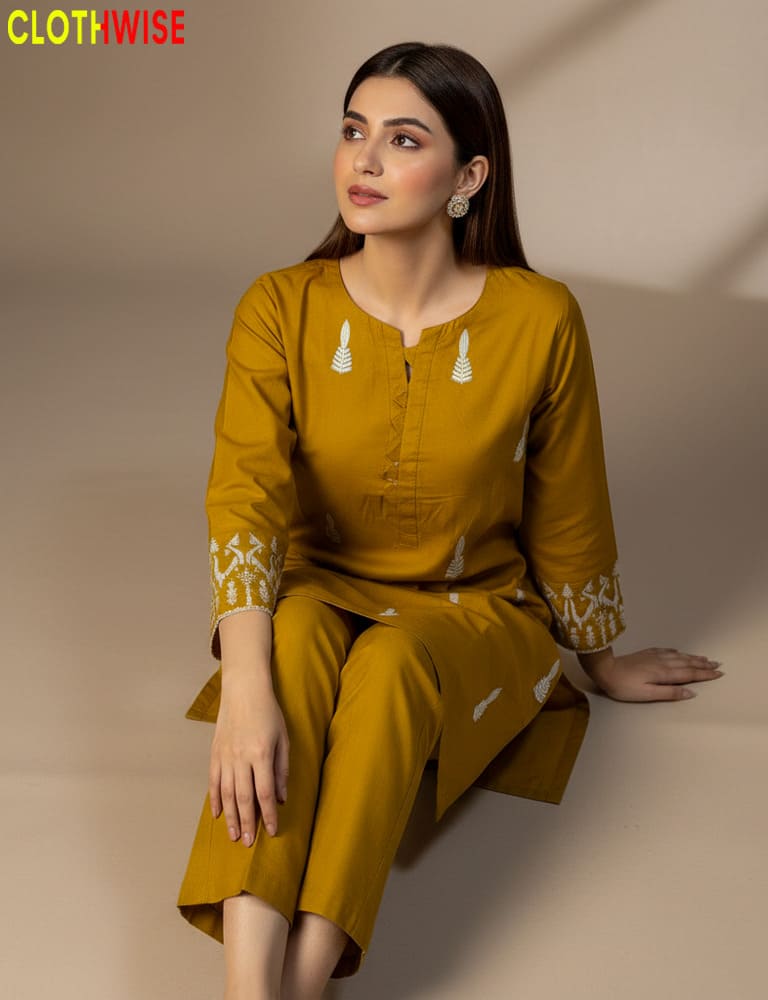 Woman wearing a mustard yellow outfit with white patterns, sitting against a beige background. Brand 'Clothwise' visible.