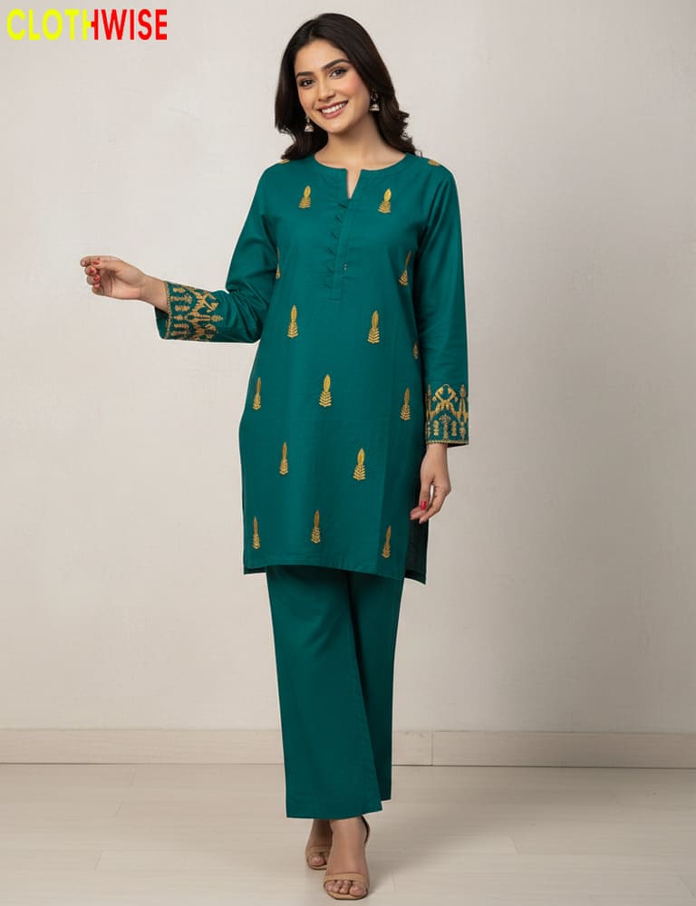 Woman wearing a green traditional outfit with gold embroidery on a plain background