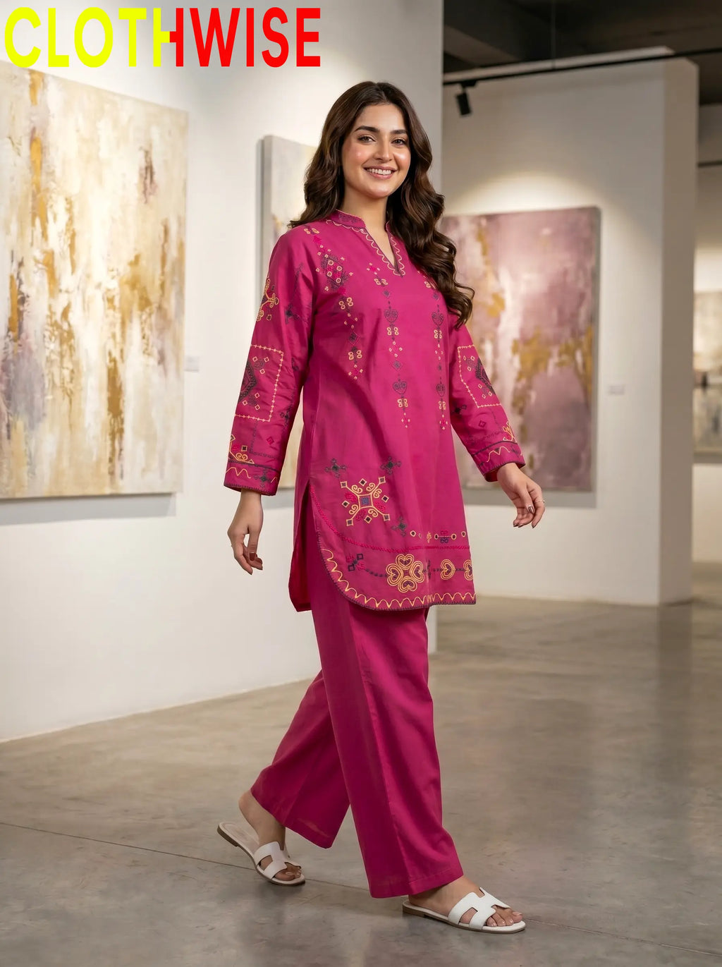 Woman wearing a pink embroidered outfit in an art gallery setting with 'CLOTHWISE' branding.