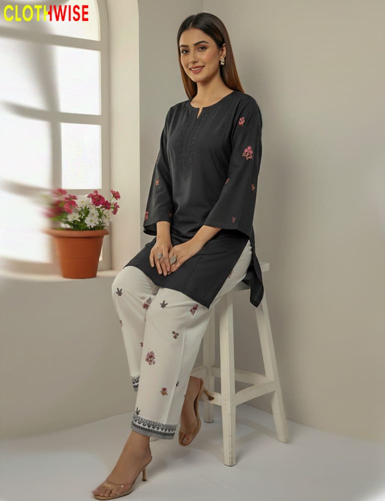 Woman sitting on a stool wearing a dark blue top and white pants with floral patterns, with 'CLOTHWISE' branding.