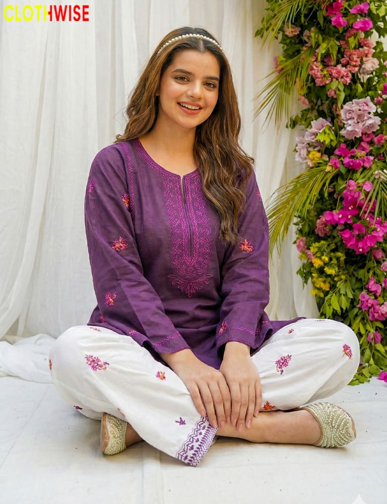 Woman wearing a purple and white embroidered outfit sitting on a floral background with 'ClothWise' branding.