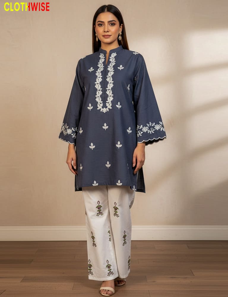 Woman wearing a navy blue embroidered kurta with white pants against a beige wall.