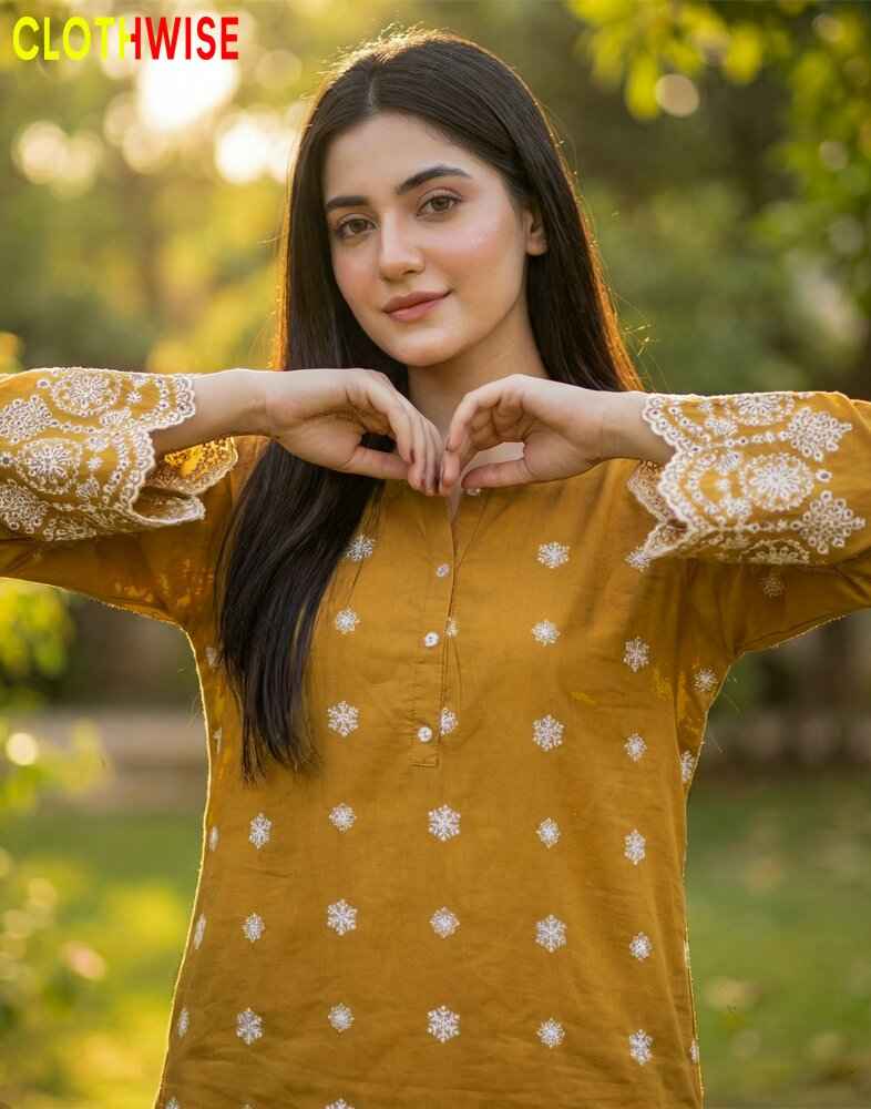 Woman wearing a mustard yellow embroidered kurta with white patterns, standing outdoors.