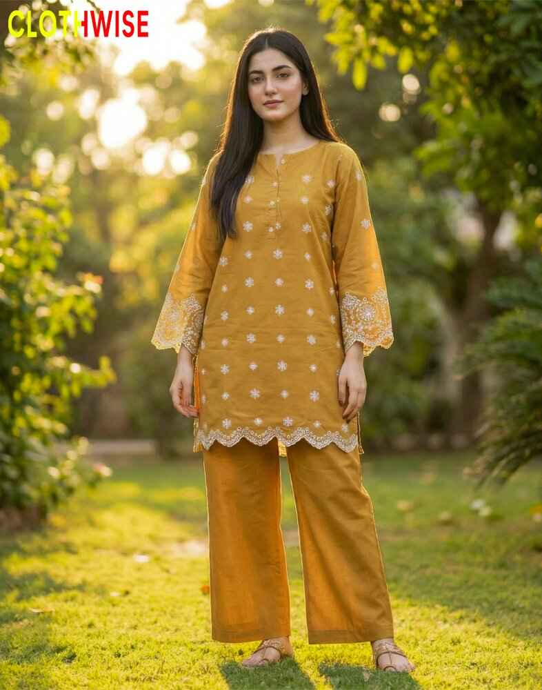 Woman wearing a mustard yellow outfit with white patterns standing in a garden.
