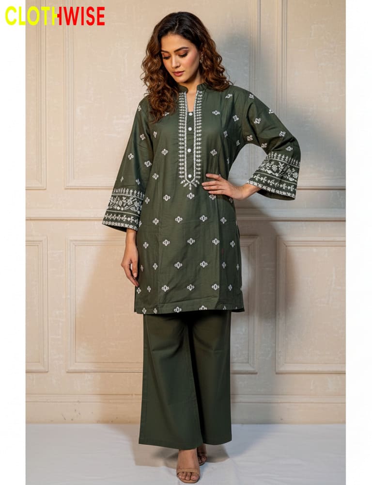 Woman wearing a green embroidered outfit with wide-leg pants against a neutral wall.