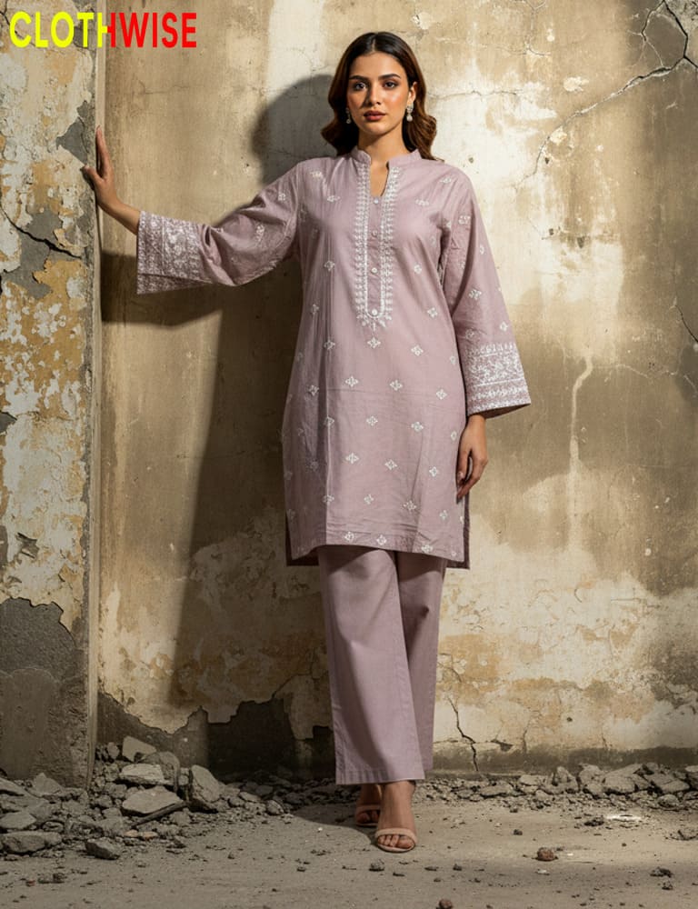 Woman wearing a light purple kurta with white embroidery against a textured wall.