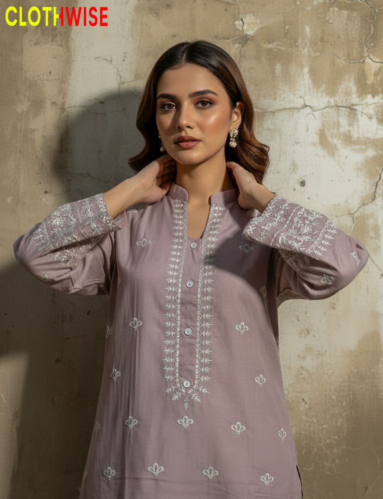 Woman wearing a light purple embroidered shirt against a textured wall with 'CLOTHWISE' branding.