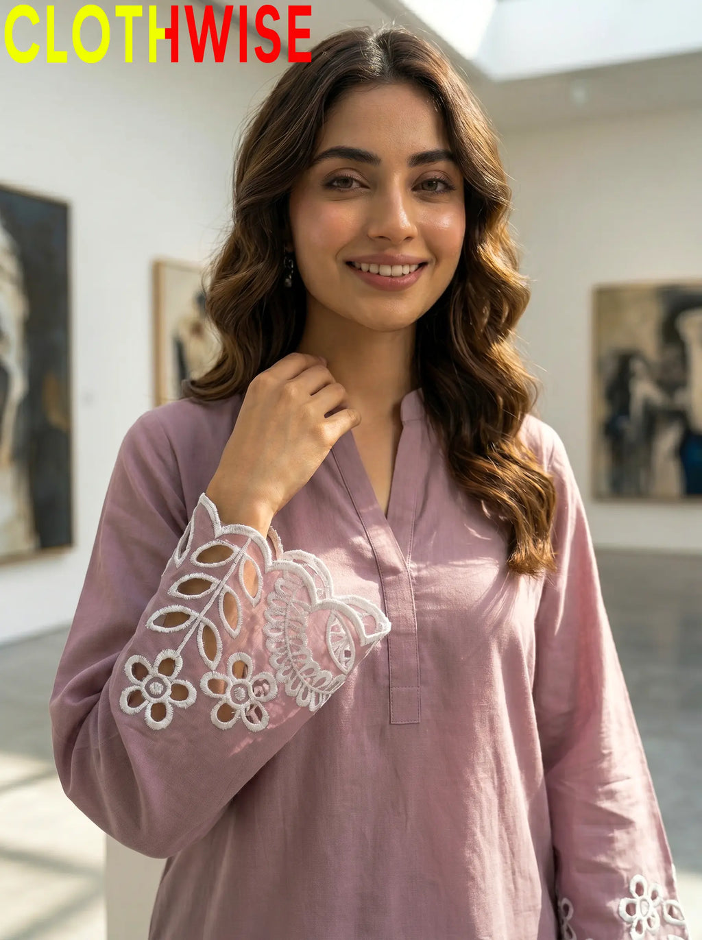 Woman wearing a pink blouse with lace details in an art gallery setting.