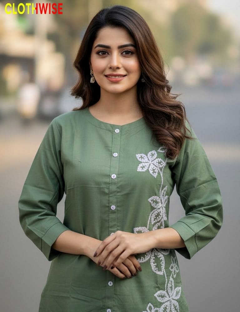 Woman wearing a green kurta with white floral embroidery, standing outdoors.