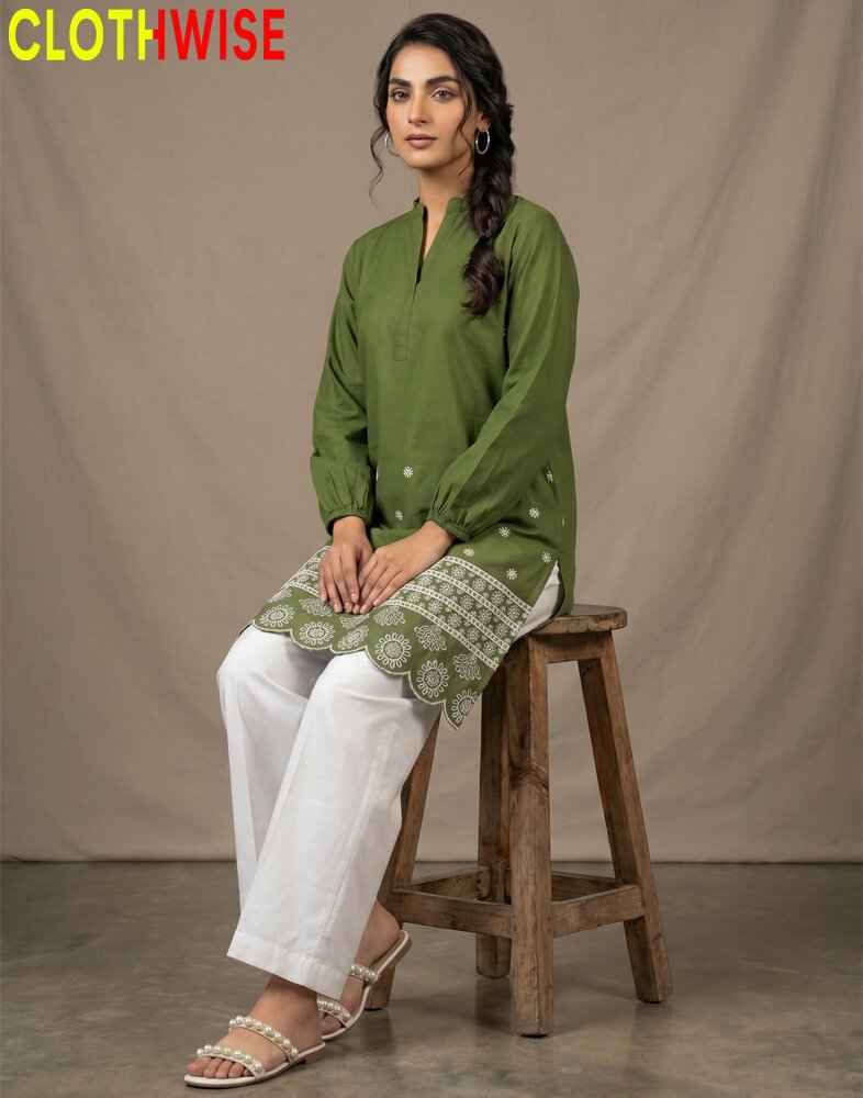 Woman wearing a green kurta with white pants sitting on a wooden stool against a beige background, with 'CLOTHWISE' branding.